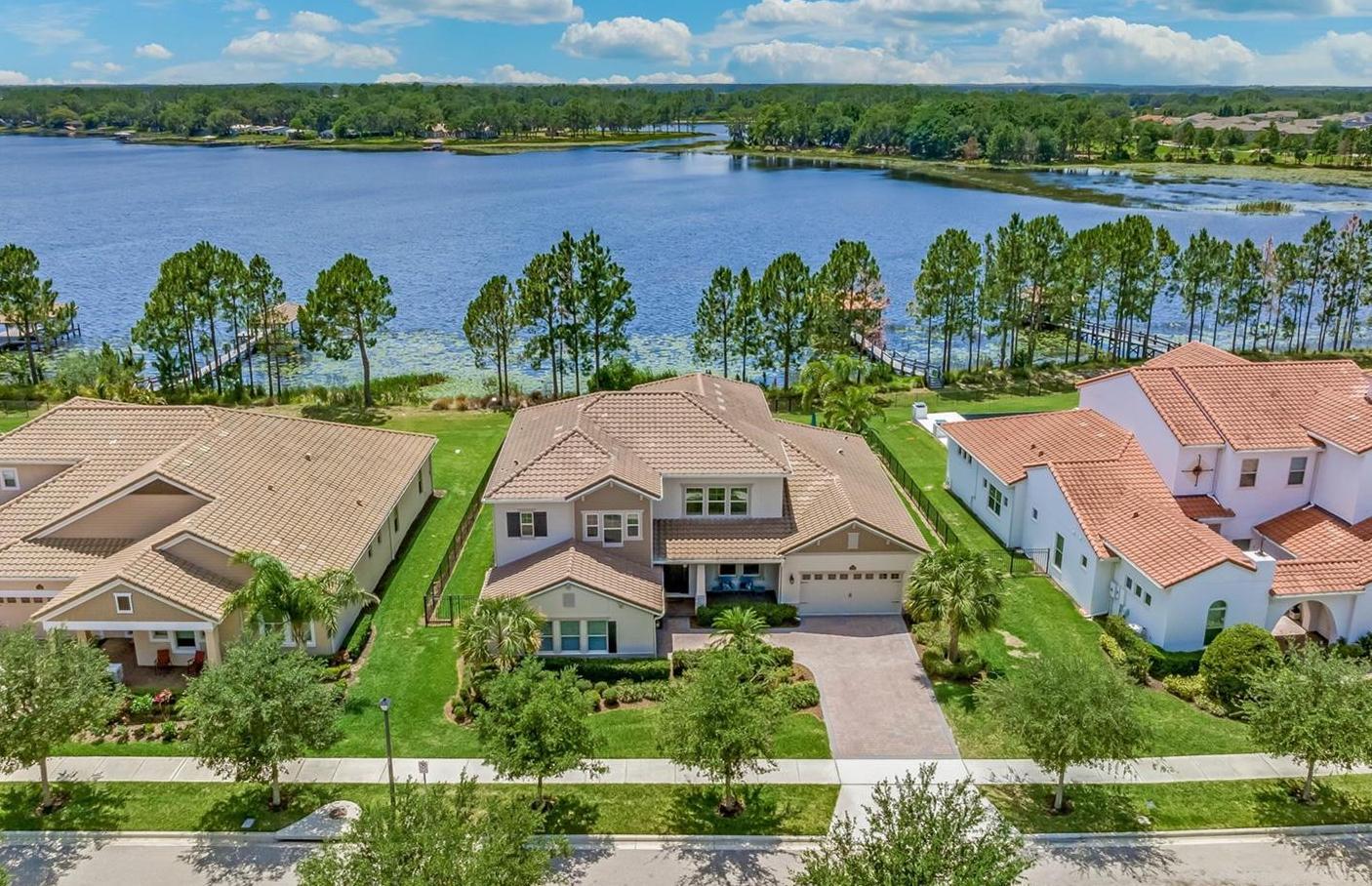 drone shot of two story home with lake and sky